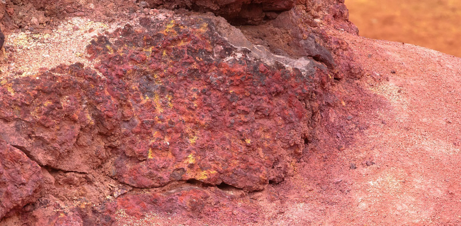 Bauxite for aluminum production - A photo of bauxite, a sedimentary rock that is the world's primary source of aluminum. The photo shows a close-up of bauxite ore, which appears as reddish-brown or rusty in color due to the high concentration of iron oxide. The texture of the bauxite is rough and grainy, with visible particles of varying sizes.