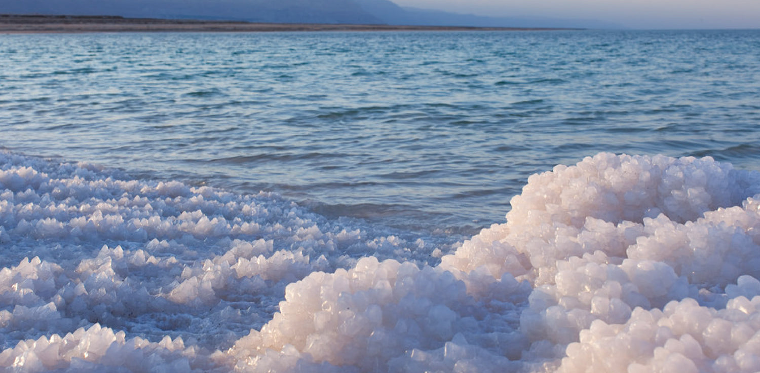 Chloride or mineral salt deposits on shore - A photo of salt or chloride deposits found along a shoreline or coast. The photo shows a close-up of crystalline structures formed by the accumulation of salt or chloride minerals on rocks, sand, or other surfaces. The color and texture of the deposits may vary depending on the specific type of salt or mineral present, but they typically appear as white