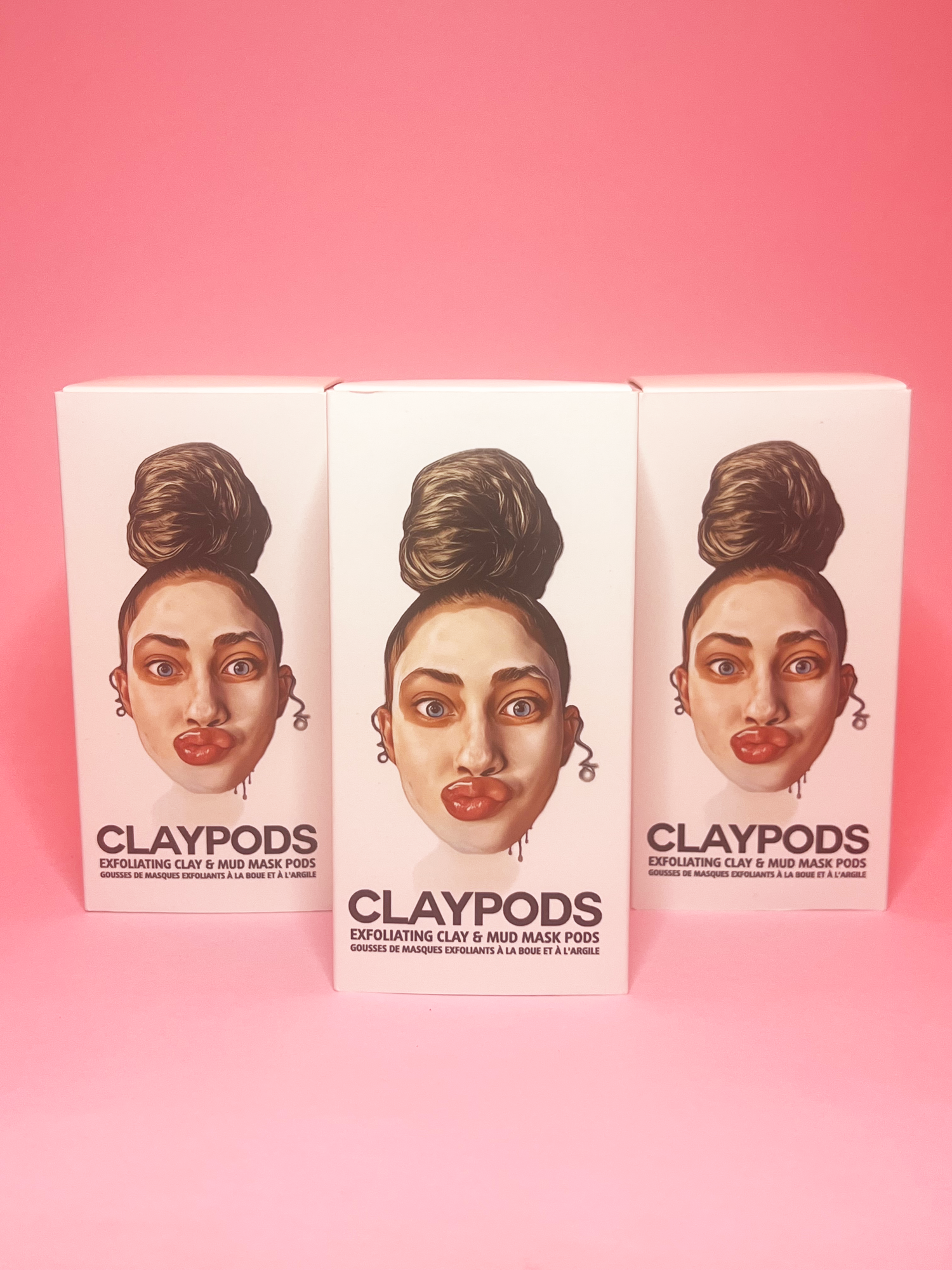 boxes of clay pods with one in front, pink background